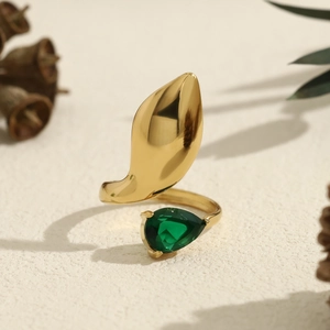 Irregular gold ring with emerald zircon and wide leaf detail in natural light