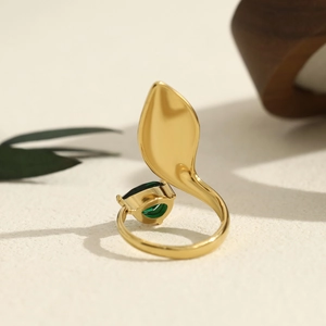 Macro shot of irregular gold ring with emerald zircon and elegant leaf detail