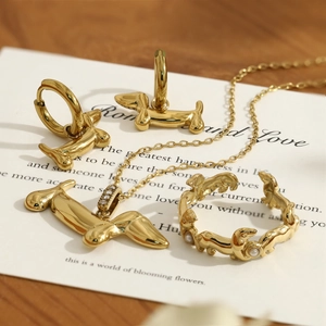 Dettaglio di un set gioielli bassotto dorato con collana, orecchini e anello su carta