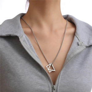Gros plan du collier à pendentif triangle imbriqué porté sur un tricot gris clair