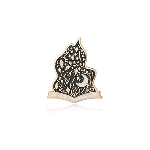Detailed close-up of an enamel book pin with crescent moon and mystical symbols