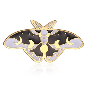 Macro view of moth enamel pin with crescent moon pattern and polished gold-plated finish