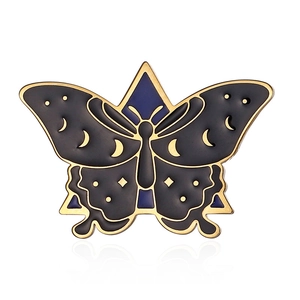 Macro view of gold enamel butterfly pin featuring crescent moon and star patterns
