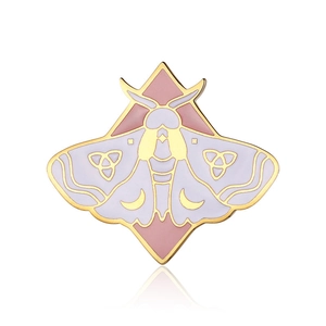 Detailed macro view of moth enamel brooch with triquetra and crescent symbols in soft lavender