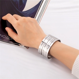 Macro detail of silver C-shaped cuff bracelets with engraved heartbeat pattern on the band