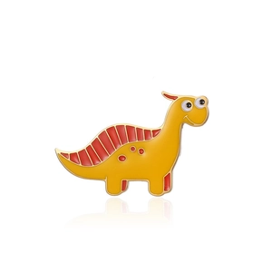 Close-up of cute yellow dinosaur enamel pin with golden metal edges and glossy finish