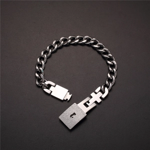 Detail of silver stainless steel Cuban chain bracelet with matte padlock and cross key