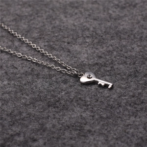 Close-up of silver heart-shaped key pendant with sparkling crystal inlay on chain
