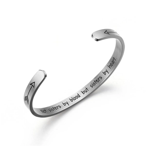 Detail of silver brushed stainless steel cuff with engraved sisterhood quote and arrows