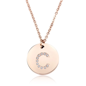 Dettaglio di collana in oro rosa con ciondolo rotondo intarsiato con lettera C di cristallo
