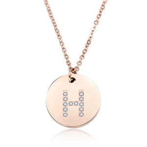 Macro di una collana in oro rosa con ciondolo rotondo e lettera H decorata con cristalli