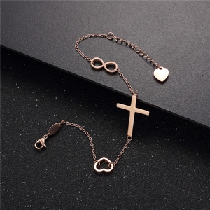 Bracciale in oro rosa con ciondoli a croce e infinito, chiusura regolabile su fondo nero