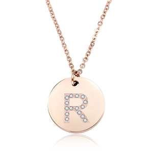 Dettaglio di un ciondolo tondo in oro rosa con lettera R scintillante in diamanti