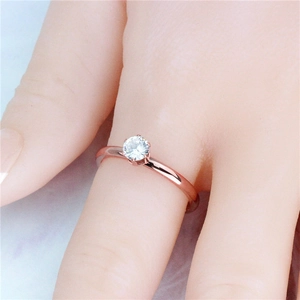Close-up van roségouden ring met een briljant geslepen steen in zes pootjes aan vinger