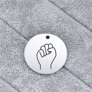 Close-up of a silver stainless steel round pendant with engraved hand gesture sign