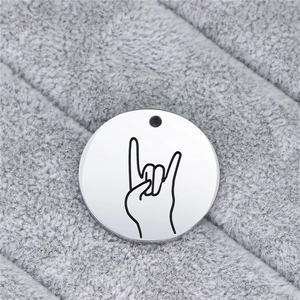 Macro shot of circular stainless steel pendant featuring laser-engraved hand sign