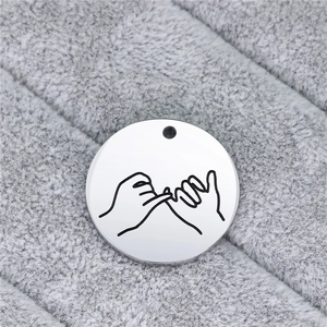 Macro detail of round stainless steel pendant with engraved pinky promise gesture art