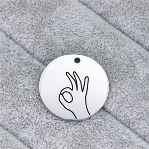 Macro close-up of polished stainless steel round tag featuring a black OK hand gesture
