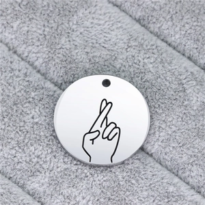 Close-up of a round stainless steel pendant featuring an engraved sign language gesture