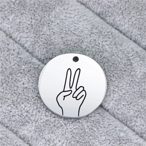 Macro shot of a stainless steel round pendant with engraved hand gesture sign on plush fabric