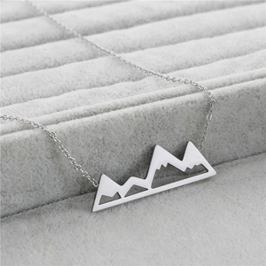 Makro-Detail von silbernem Berg-Anhänger auf grauem Samt-Schmuck-Display-Pad