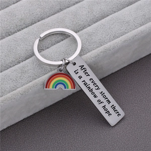 Titanium steel keychain with rainbow charm and engraved quote on gray jewelry tray