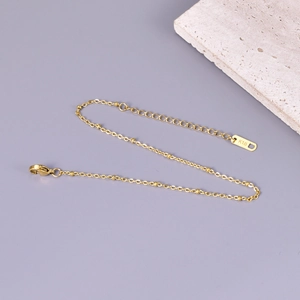 Elegante tobillera de oro rosa de 18K con cuentas y cierre de langosta sobre fondo pétreo