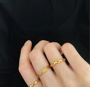 Three gold-plated titanium steel rings with chain and wave designs worn together