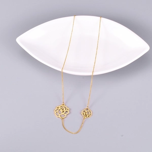 Detail showing gold dual hollow camellia rose pendants on a delicate O-chain necklace