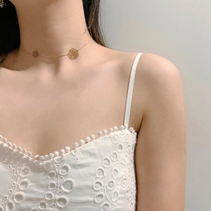 Detail of delicate gold necklace with hollow camellia pendants on female neck