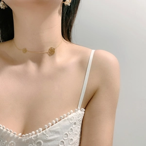 Detail of gold choker necklace with hollow rose pendants worn by a model