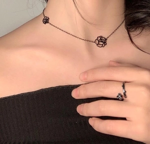 Detail of black hollow camellia choker necklace and matching ring on model