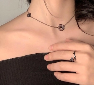 Detail of black cutout camellia flower choker and branch style ring set for women