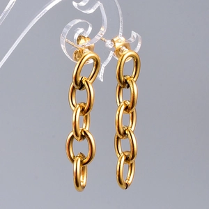 Macro detail of gold long chain drop earrings with textured oval interlocking links