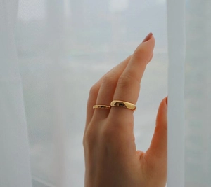 Nahaufnahme von minimalistischen vergoldeten breiten und schmalen Ringen am Finger