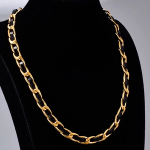 Collana a catena in acciaio placcato oro 18K con pelle nera intrecciata su un busto nero