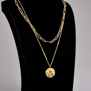 Detail of double-layer gold necklace with paperclip chain and angel relief pendant