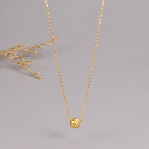 Primo piano della collana in acciaio dorato con ciondolo a sfera geometrica taglio diamante
