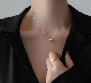 Vista dettagliata della collana con perla testurizzata a rombi e anello abbinato su modella