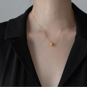Collana minimalista in acciaio inossidabile con pendente a sfera d'oro traforata su modella