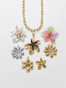 Flat lay of acrylic flower pendants and golden chain necklace on white texture