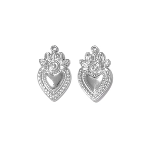 Primer plano de colgantes de corazón plateados con relieves vintage y detalles de corona