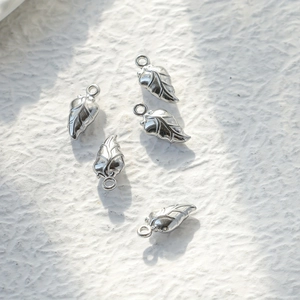 Detailed macro view of five silver leaf-shaped metal pendants with realistic leaf veins