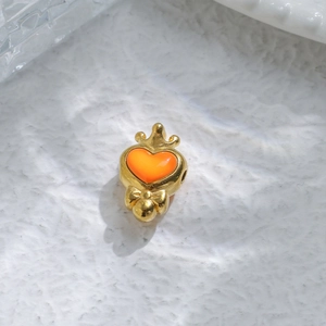Close-up of golden crown heart charm bead with orange enamel detail for DIY jewelry