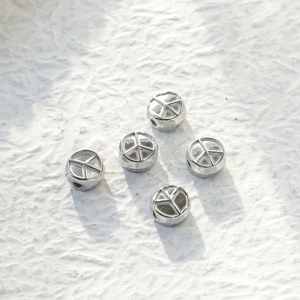 Macro detail of silver hollow chain beads with embossed star pattern on white background