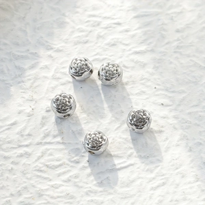 Detailed macro view of five silver rose-shaped stainless steel beads for DIY jewelry making