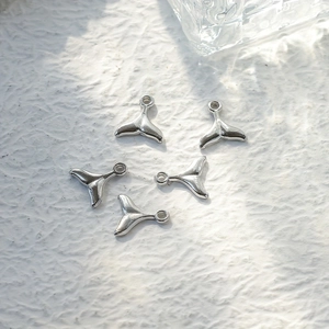 Detailed view of five mirror-polished silver whale tail charms for DIY jewelry making