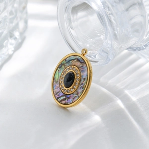 Vue macro d'un pendentif ovale plaqué or avec nacre et incrustation de pierre noire