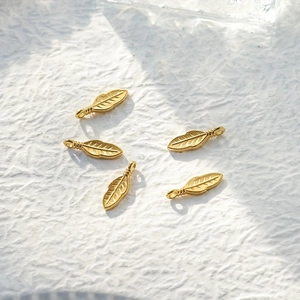 Detailed macro view of five golden feather pendants with intricate metallic texture carvings