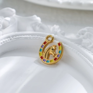 Golden horseshoe pendant with horse head detail and colorful dots on white tray